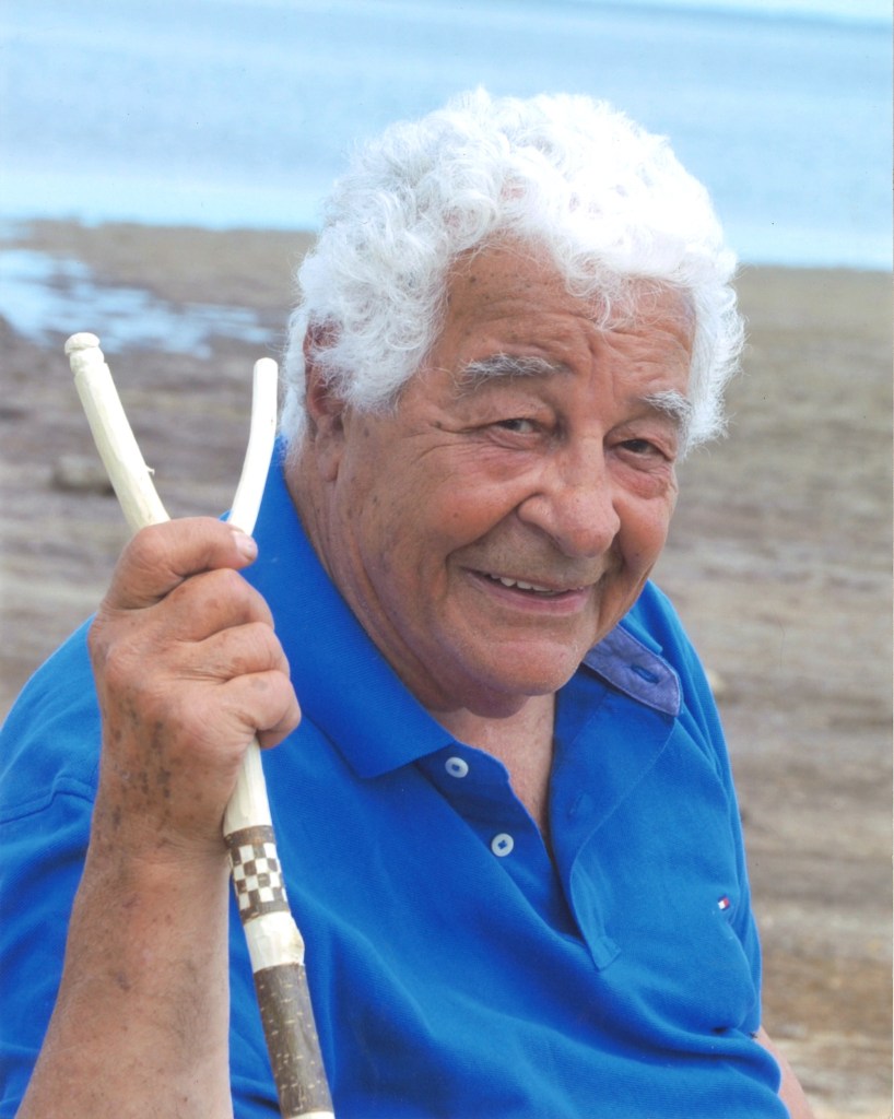 Antonio Carluccio on an Australian beach holding a wooden foraging stick