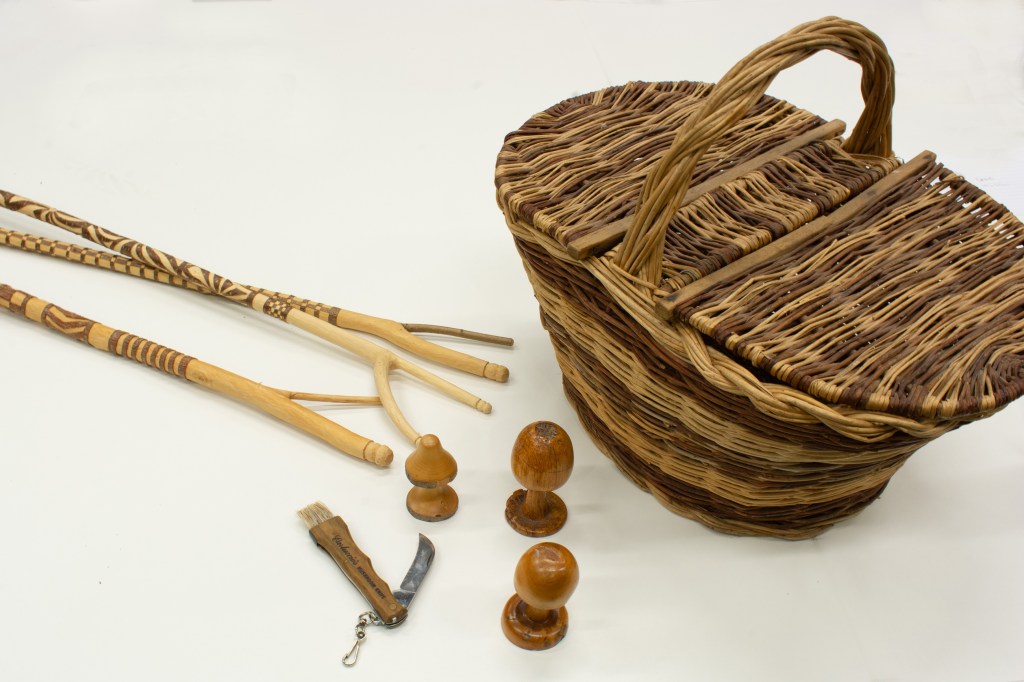 Carved hazel sticks with a wicker lidded mushroom basket, knife and wooden mushrooms