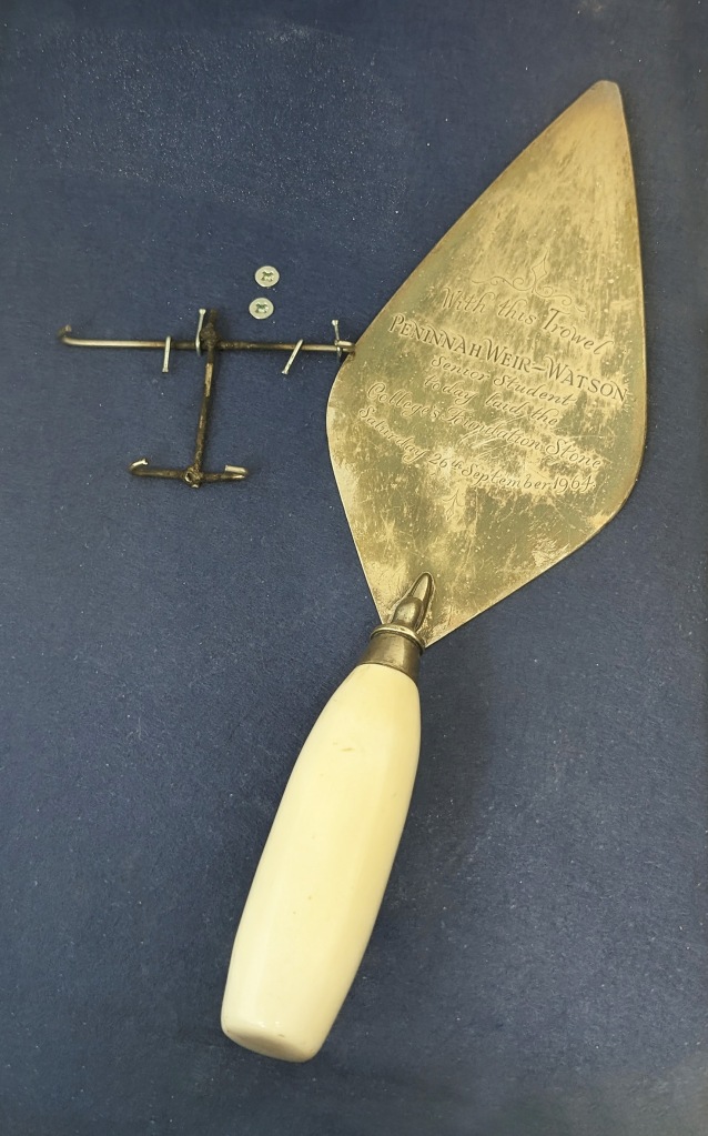A silver commemorative trowel with engraving on the flat metal surface.