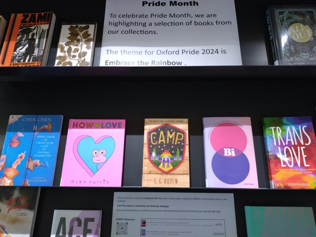 A library display shelf contains five books on LGBTQ+ themes, along with information sheets about Oxford Pride and the LGBTQ+ resources list